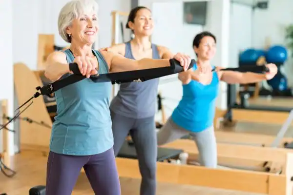 Toning Arms After 60: Empowering Womens Fitness Through Effective Weight Training 2 older woman doing weight training Bedfordshire and resistance in the gym to tone upper arms
